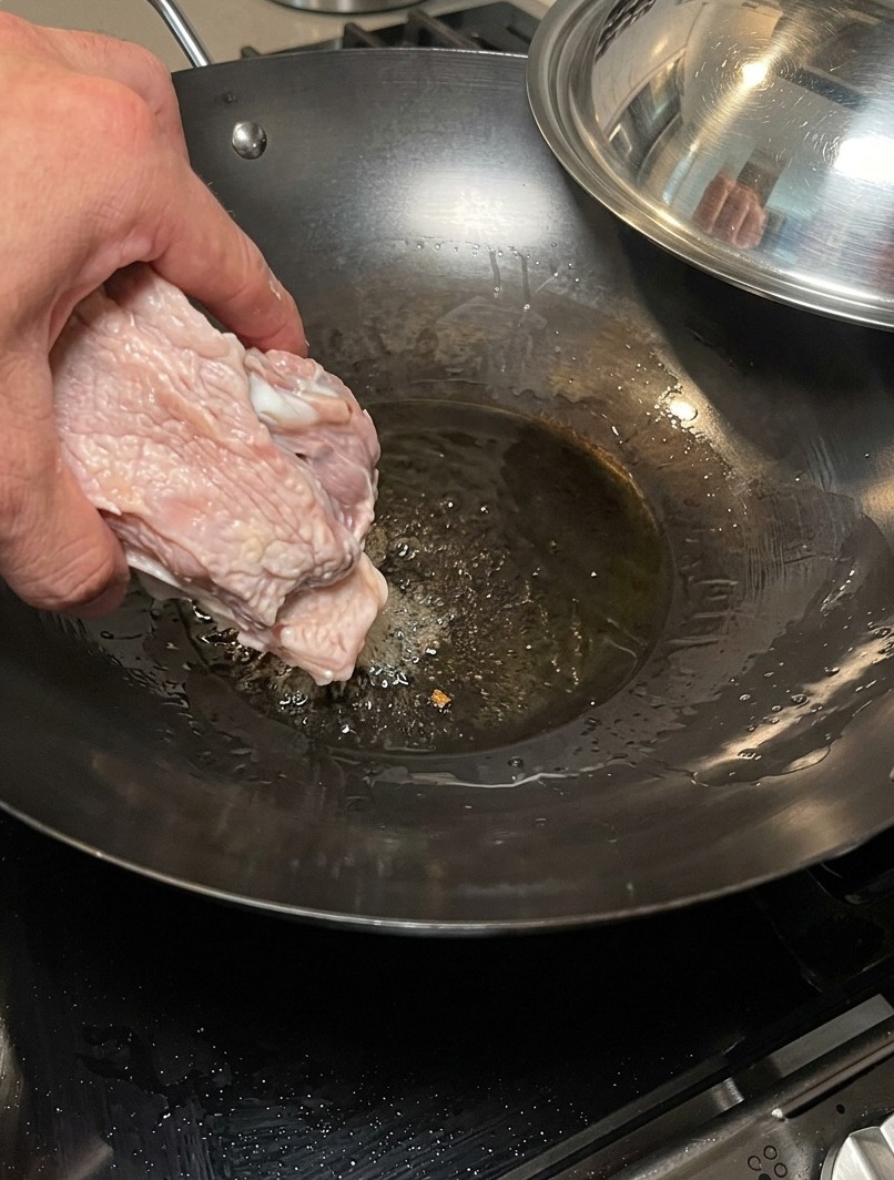Os de porc saisis dans un wok chaud et sec pour développer une base de saveur rôtie.
