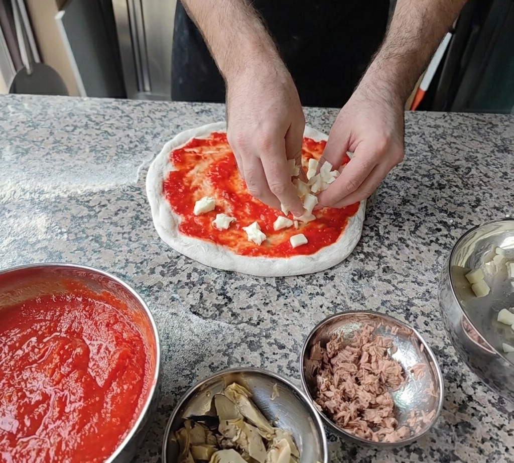 Des petits dés de mozzarella fraîche blanche parsemés sur la base de sauce tomate.