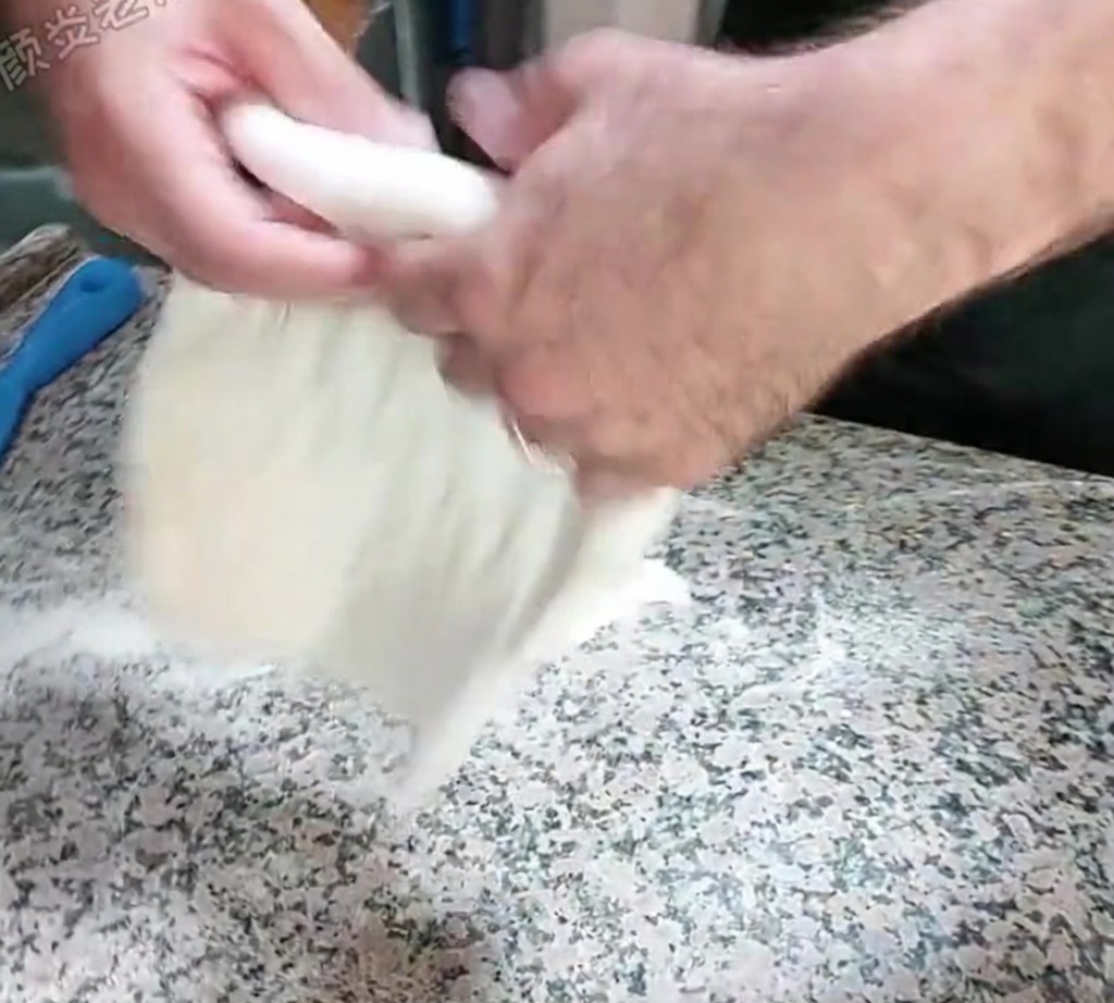 La pâte est étirée à la main par une technique de claquage sur un comptoir fariné.