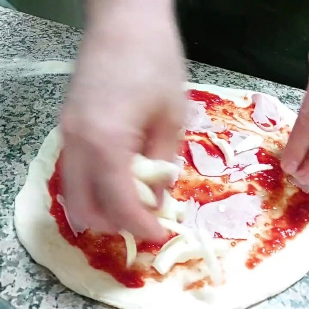 Des morceaux de fromage mozzarella ajoutés sur la base de la pizza.