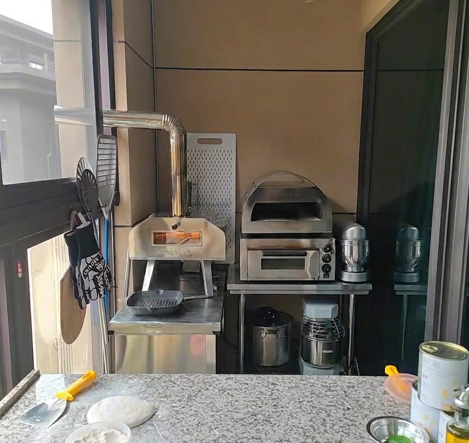 Mains étalant délicatement une boule de pâte à pizza fermentée sur un plan de travail fariné.