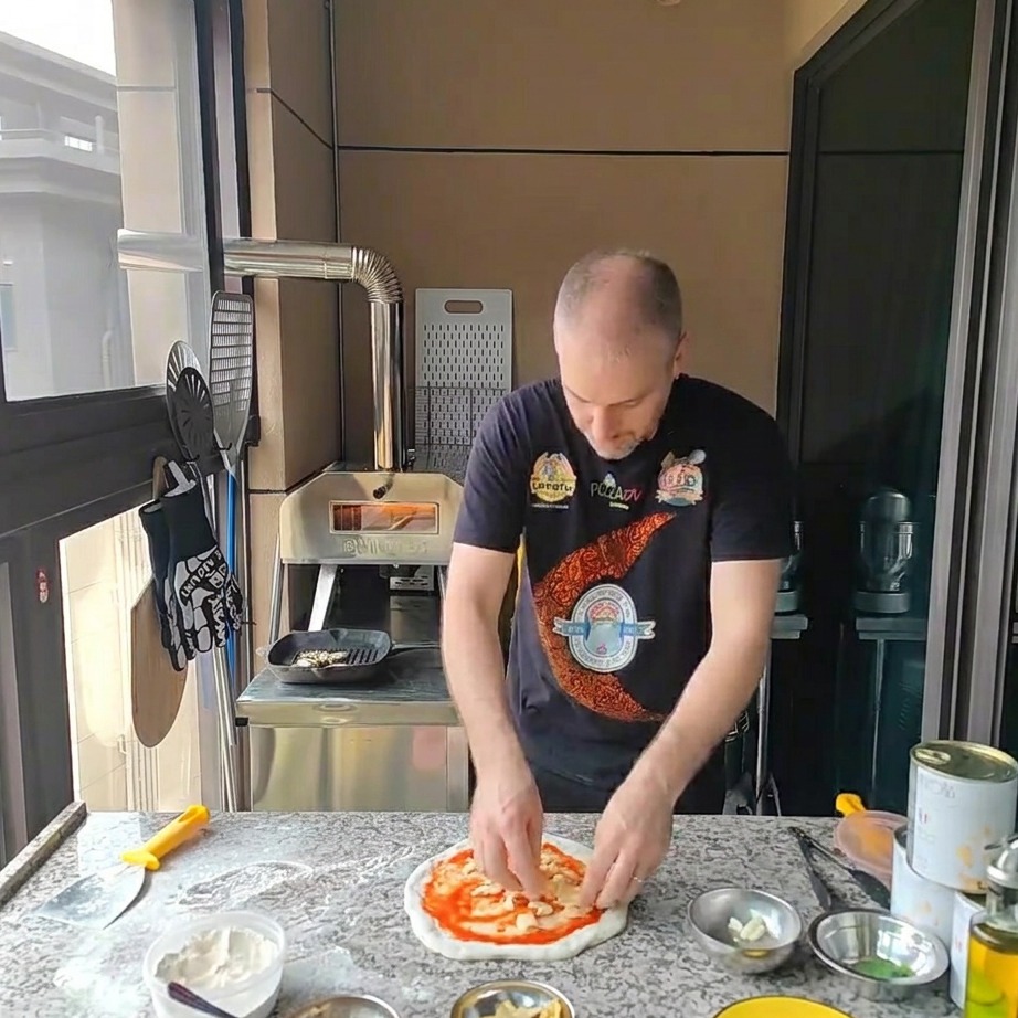 Fromage mozzarella râpé saupoudré sur la base de pizza garnie de sauce tomate.