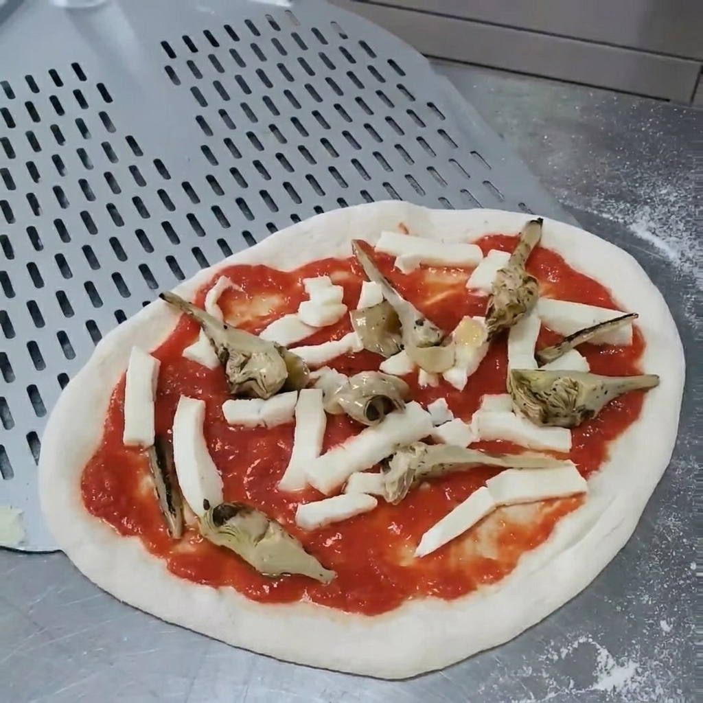 Des mains ajustant la position des artichauts sur la pizza crue pour assurer une répartition uniforme.