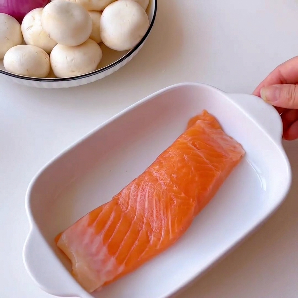 Champignons de Paris frais coupés soigneusement en fines lamelles sur une planche à découper en bois.