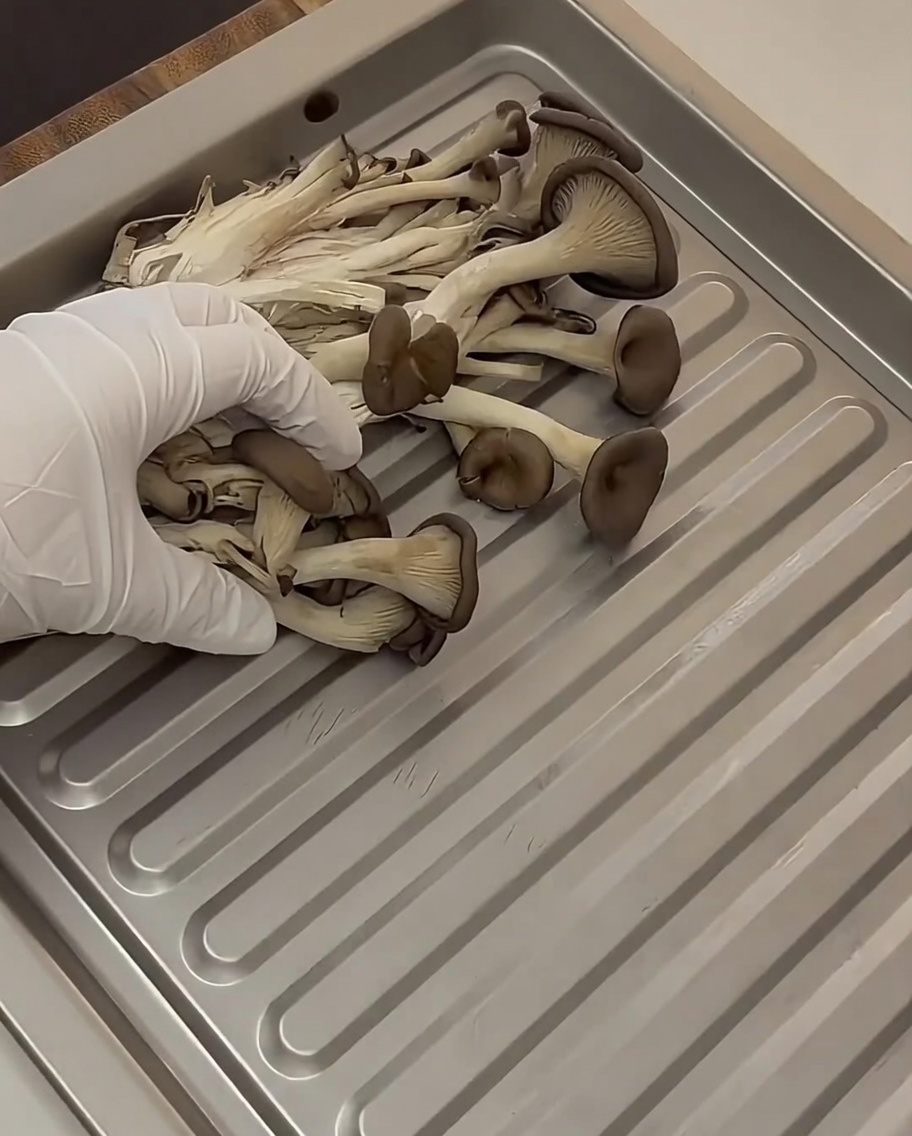 Un plateau de cuisson rempli de champignons émincés, danneaux doignon et de kimchi vieilli.