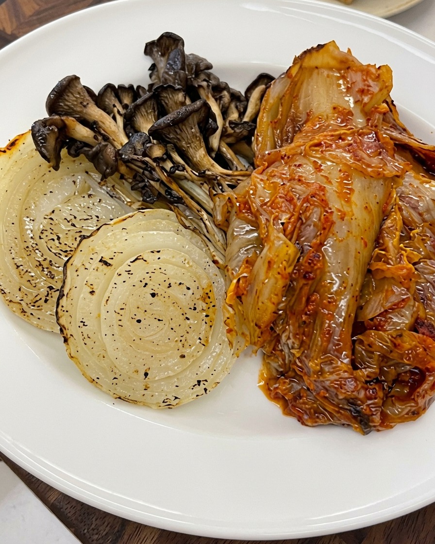 Graines de sésame saupoudrées sur les légumes rôtis et le kimchi dans une assiette.
