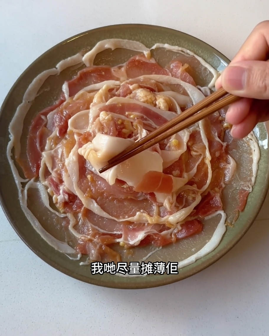 Tranches de poitrine de porc marinées soigneusement étalées en une seule couche sur une assiette à laide de baguettes.