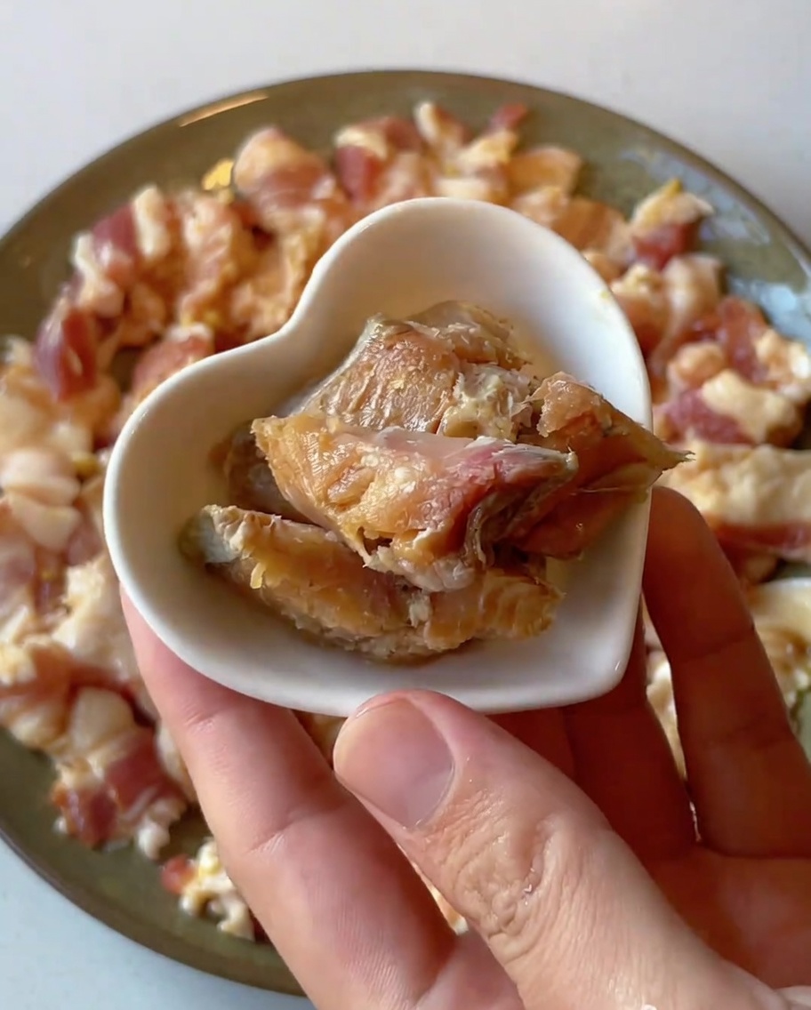 Gros plan de petits morceaux de poisson salé placés sur une assiette de porc cru mariné.