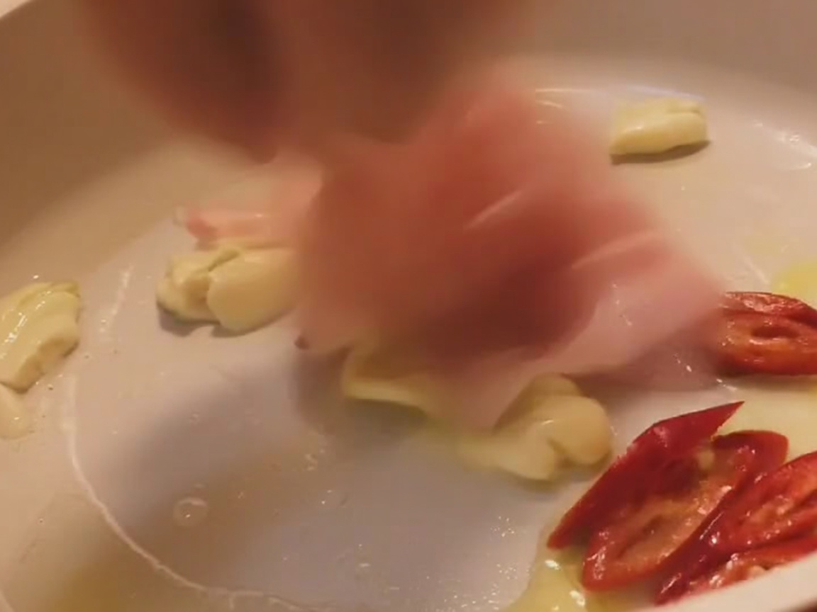 Lamelles de poitrine de porc sautées dans une poêle claire avec de lail et des tranches de piment rouge.