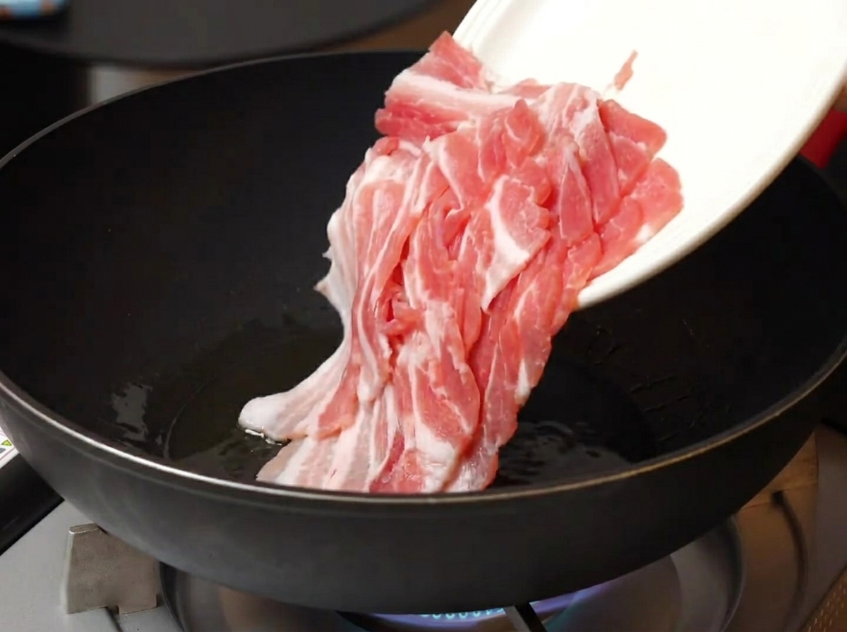 Tranches de poitrine de porc crues ajoutées dans une poêle chaude huilée.