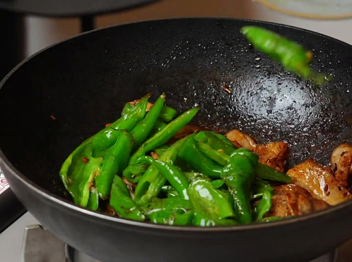Piments grillés mélangés au porc dans un wok.