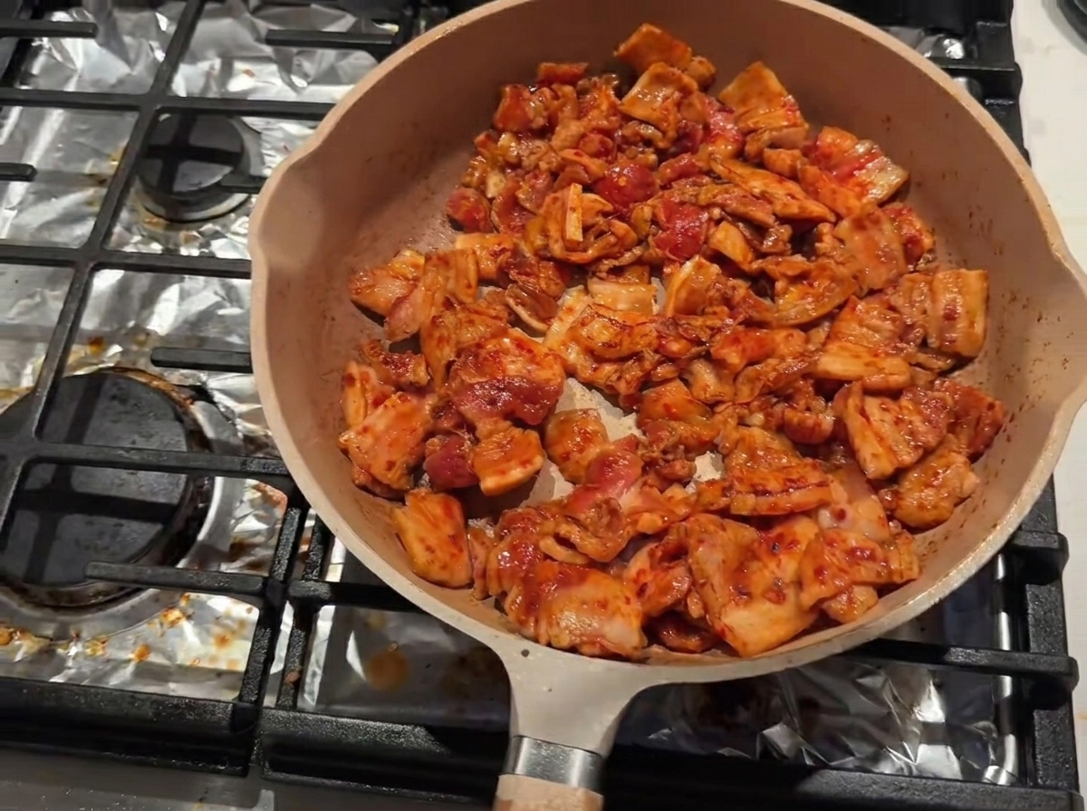 Poitrine de porc saisie dans une poêle avec du vin de cuisine ajouté le long du bord intérieur.