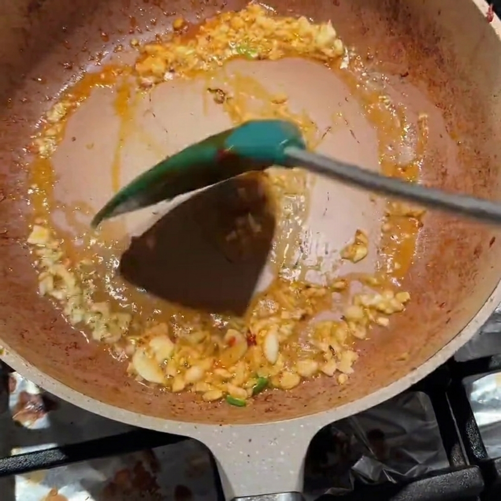 Ail haché et pâte de haricots Pixian mélangés dans une poêle.