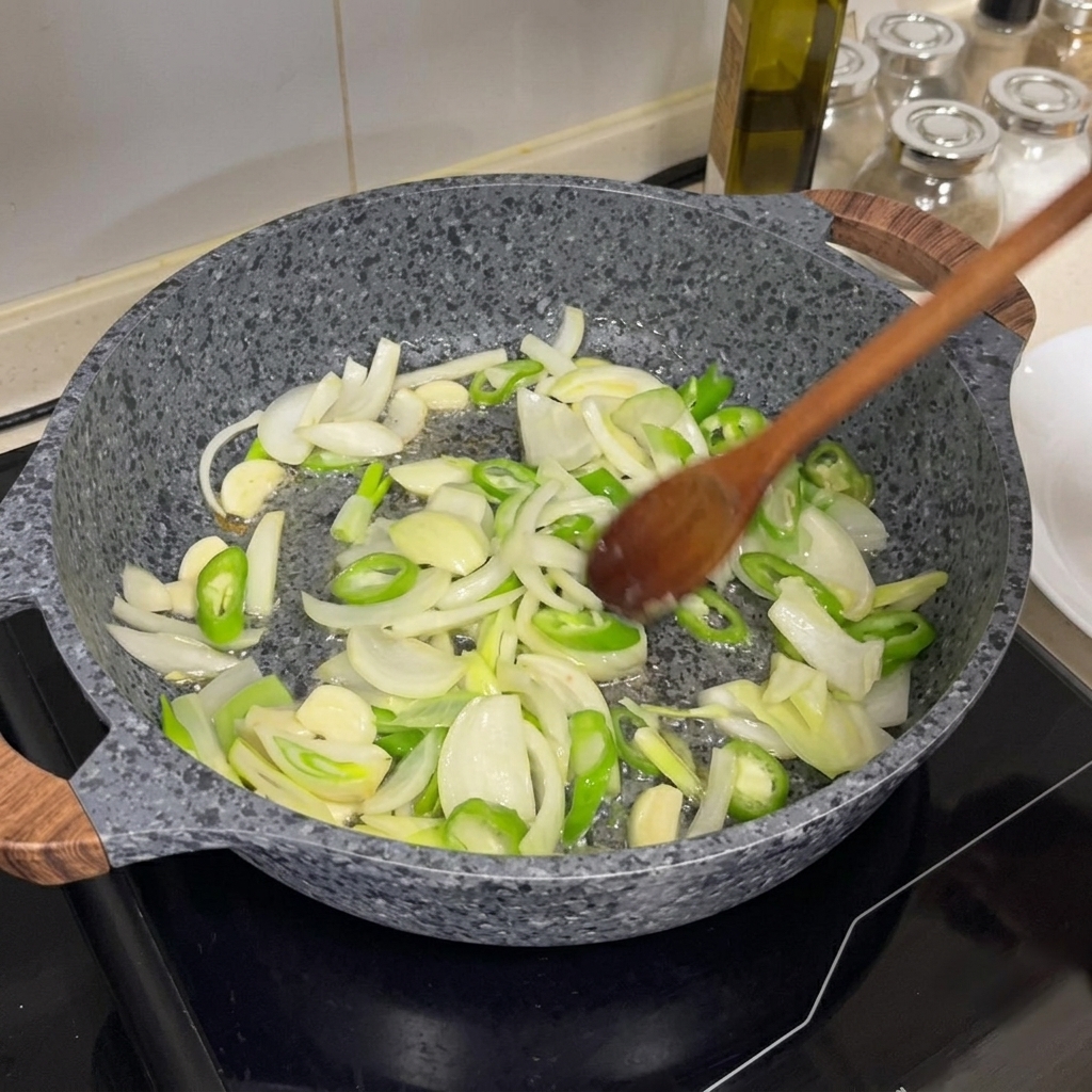 Oignons, piments verts et ail sautés dans une poêle chaude avec une cuillère en bois.