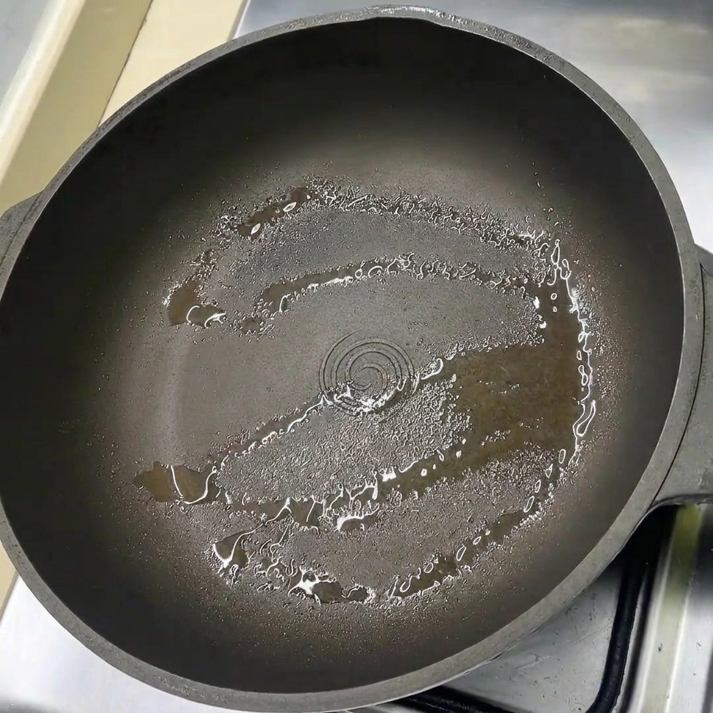 Tranches de poitrine de porc disposées dans une poêle légèrement huilée.