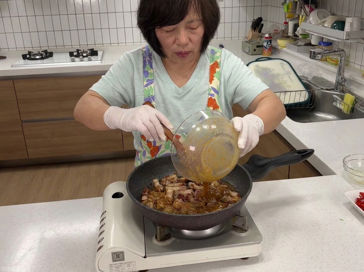 Sauce sombre à la pâte de soja versée depuis un bol dans une poêle contenant le porc doré.