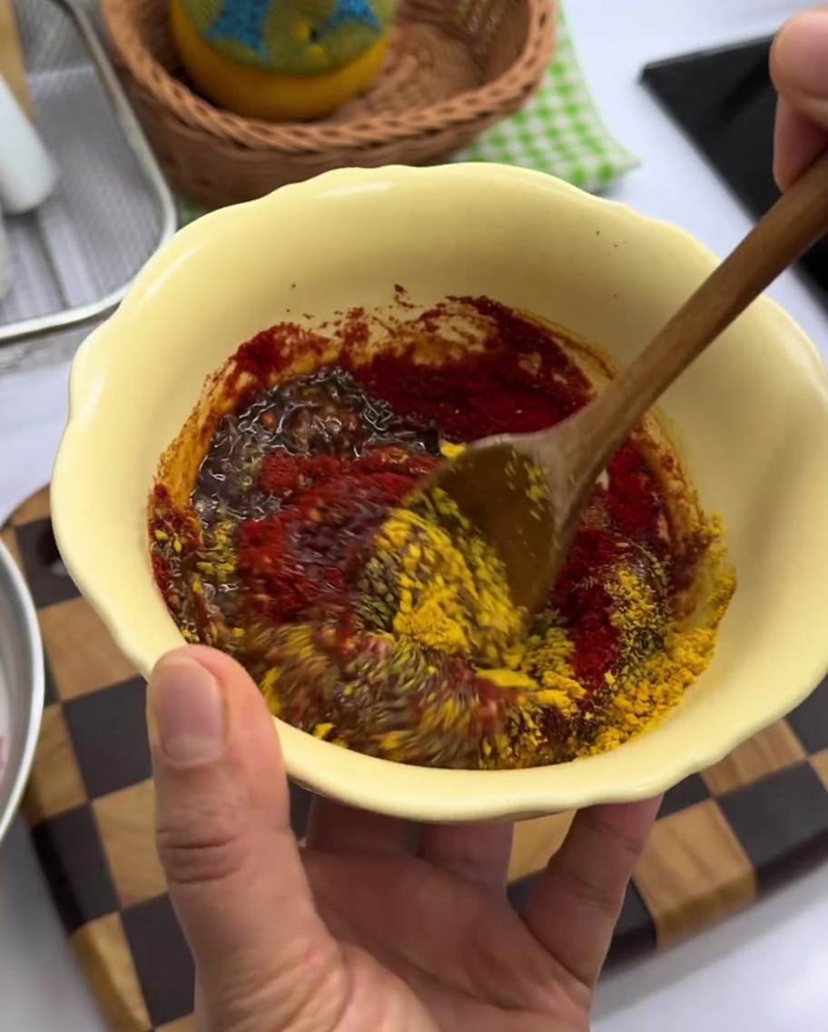Pâte dépices rouge épaisse mélangée dans un bol jaune.