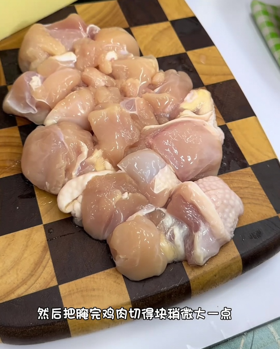 Morceaux uniformes de cuisse de poulet crue sur une planche à découper en bois.