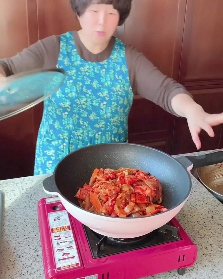 Une poêle remplie de poitrine de porc, de calamar et de légumes sautés, couverte dun couvercle en verre transparent.