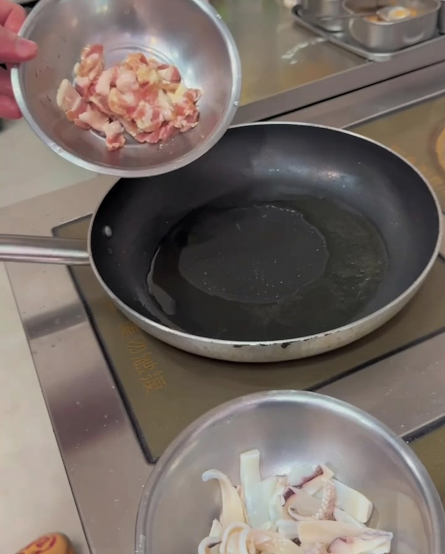 Des lanières de poitrine de porc grésillant dans une poêle chaude, avec des bords dorés.