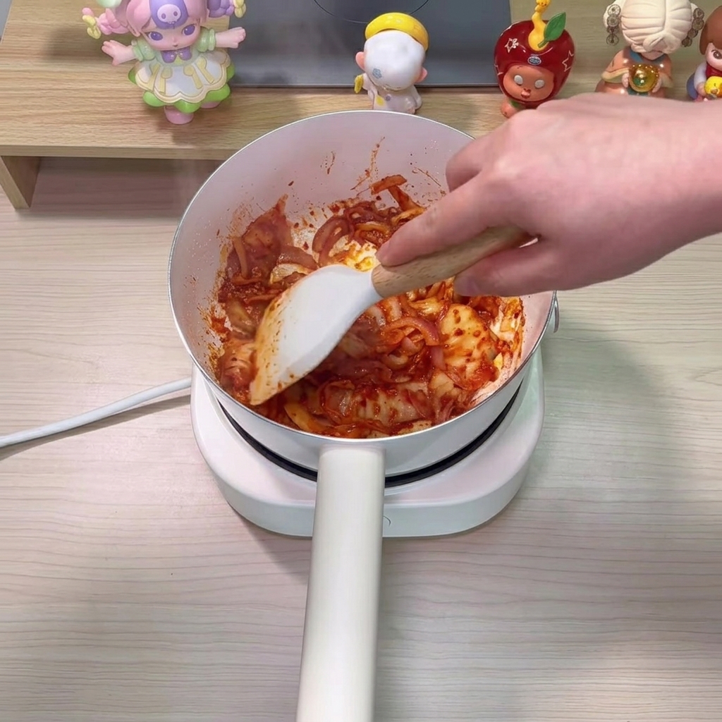 Eau claire versée dans la casserole, se mélangeant avec le kimchi et les oignons sautés.