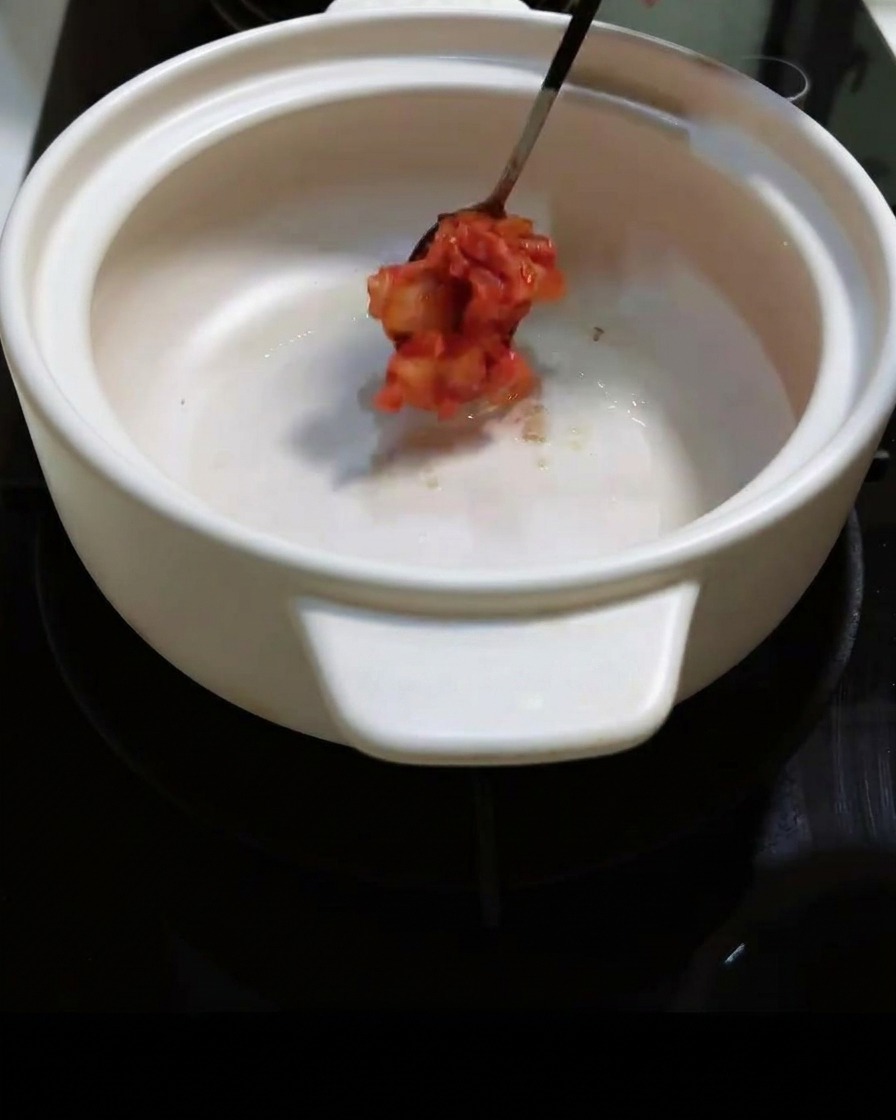 Du kimchi épicé haché est ajouté dans la marmite et mélangé.
