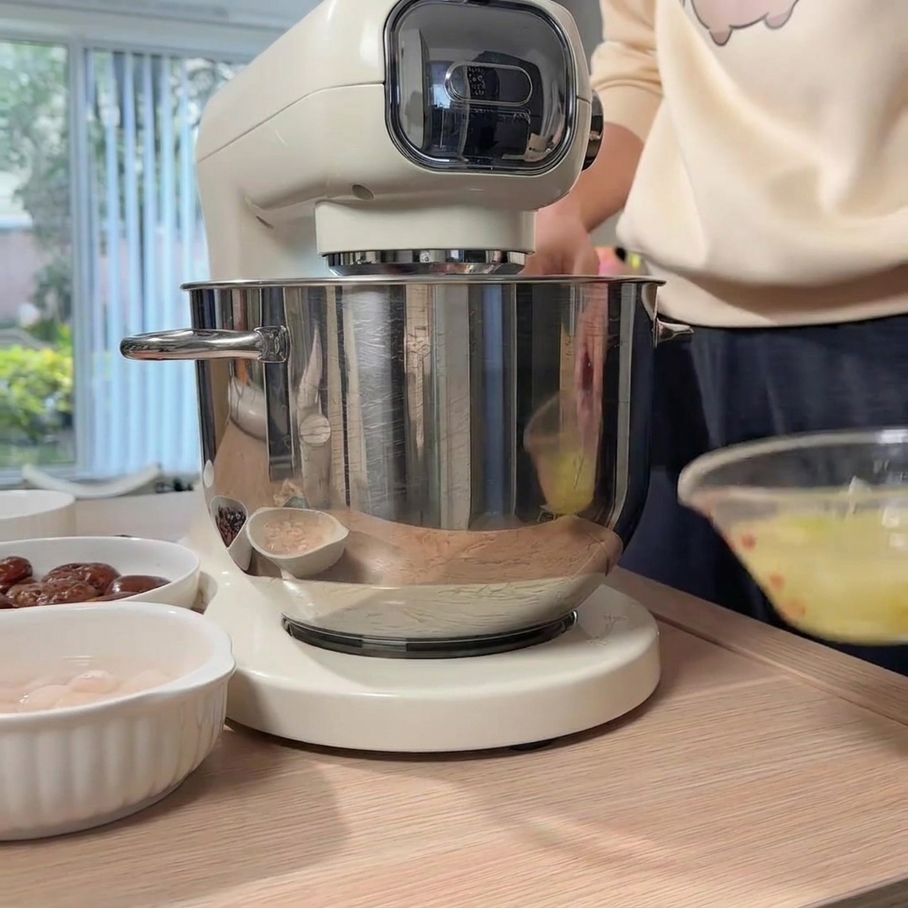 Une main versant leau gingembre-ciboule dans le bol du robot contenant le poulet haché.