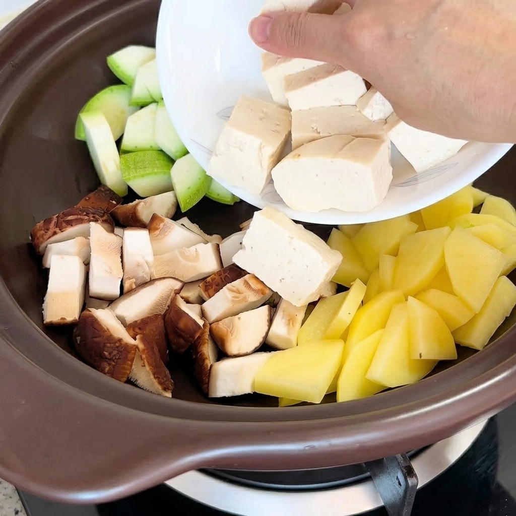Morceaux de tofu et palourdes placés dans la marmite avec les autres ingrédients.
