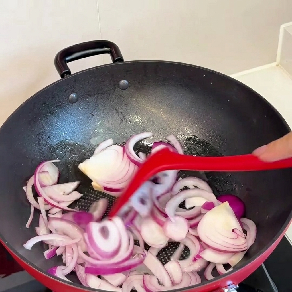 Du kimchi ajouté dans la poêle avec les oignons sautés.