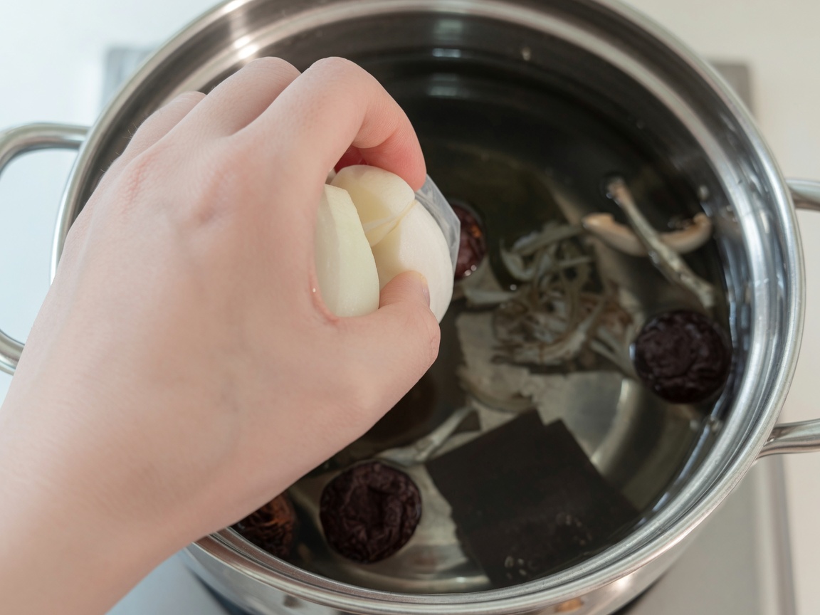 Eau bouillante dans une casserole contenant varech, anchois, champignons shiitake, oignon et radis.