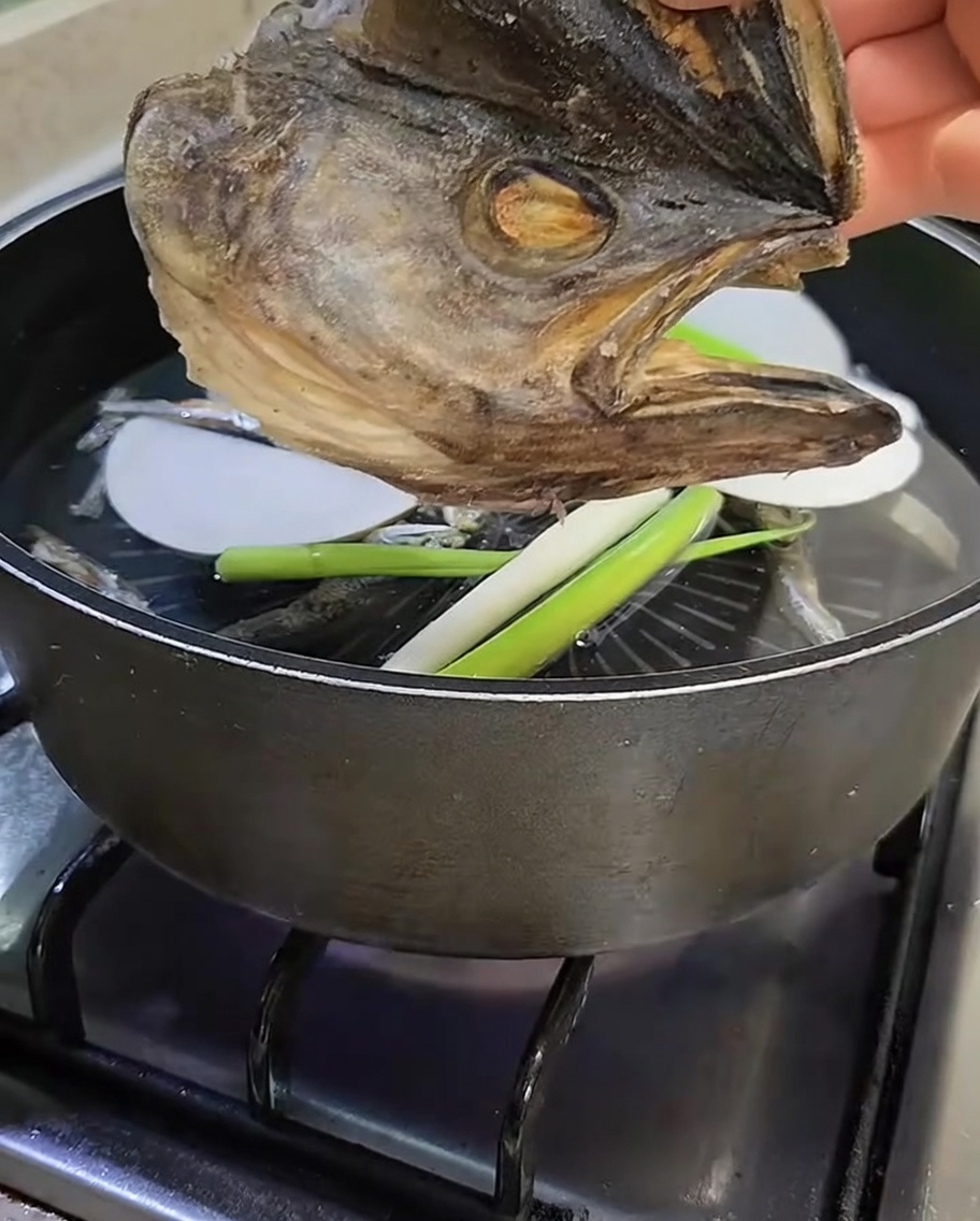 Une tête de colin séchée tenue au-dessus de la marmite.
