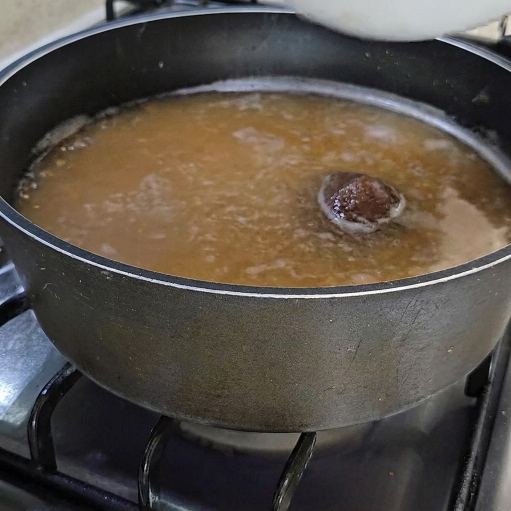Un bol dascidies orange ajoutées au bouillon de soja mijotant.