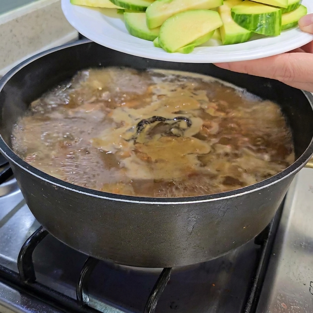 Tranches de courgettes et enoki ajoutés dans la marmite.