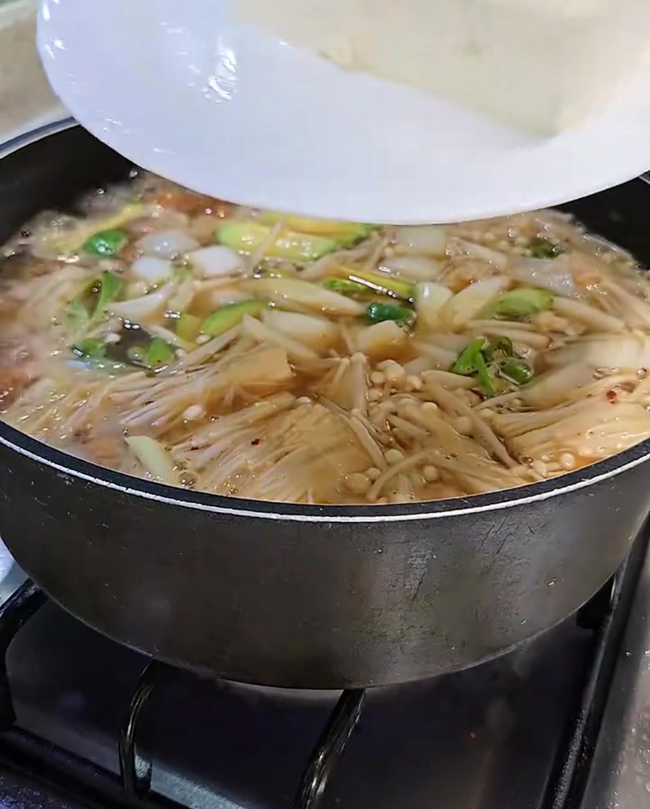 Tranches de tofu blanc transférées dans le ragoût bouillonnant.