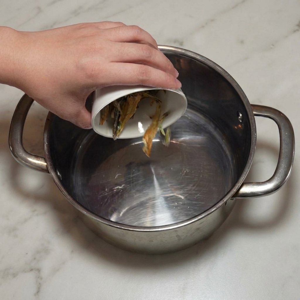 Anchois séchés nettoyés versés dans une marmite en acier inoxydable.
