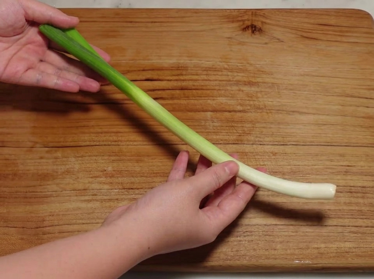 Oignon vert coupé en petits tronçons sur une planche à découper.