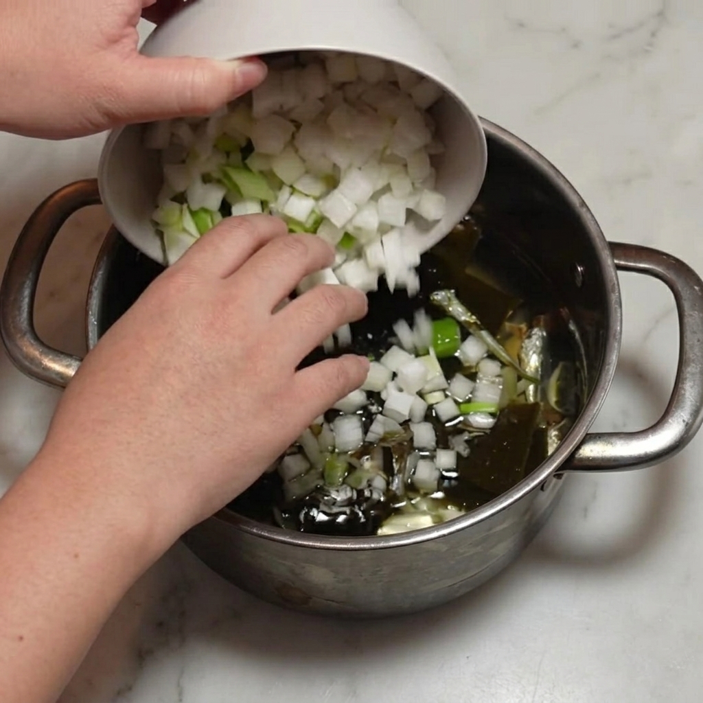 Radis en dés et oignon vert versés dans la casserole danchois et de kombu.