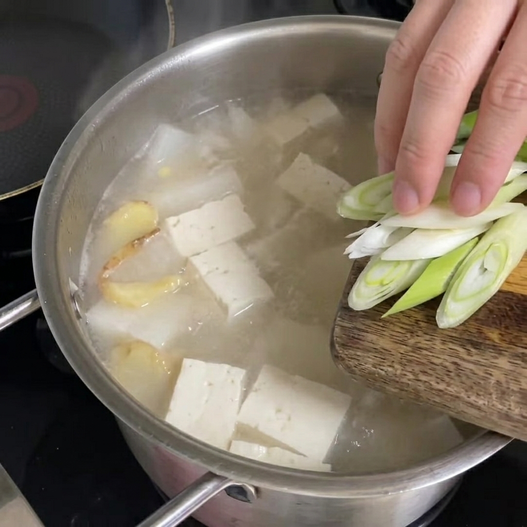 Oignons nouveaux hachés parsemés sur la soupe bouillante.