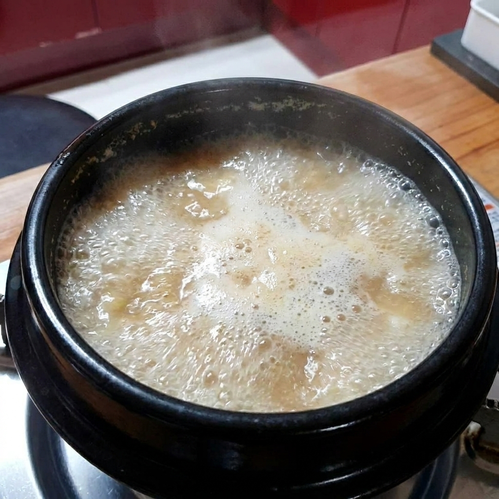 De lail haché ajouté au ragoût de pâte de soja en ébullition.