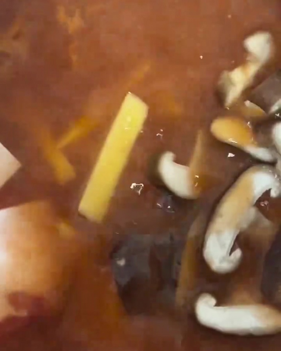 Tranches de champignons shiitake frais placées dans le ragoût.