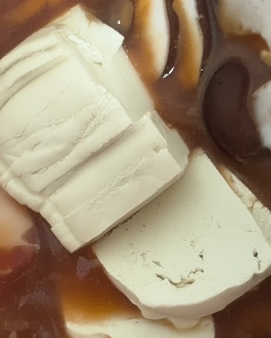 Tranches de tofu blanc doux ajoutées au ragoût frémissant.