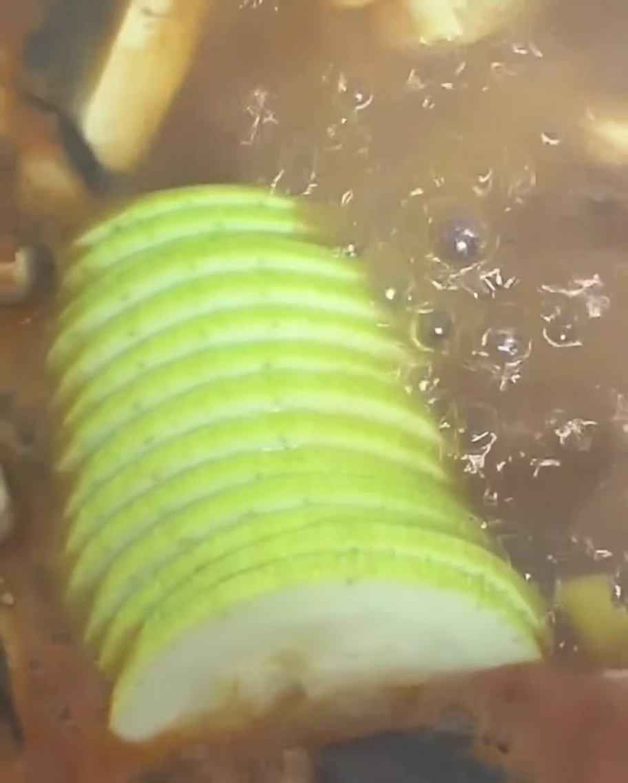 Tranches de courgette verte ajoutées au ragoût bouillonnant.