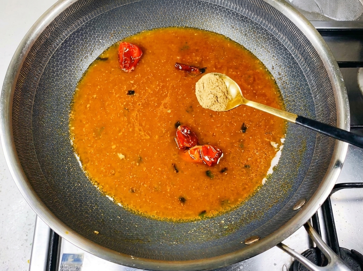 Mélange dépices saupoudré dans un bouillon bouillonnant de couleur orange dans le wok.