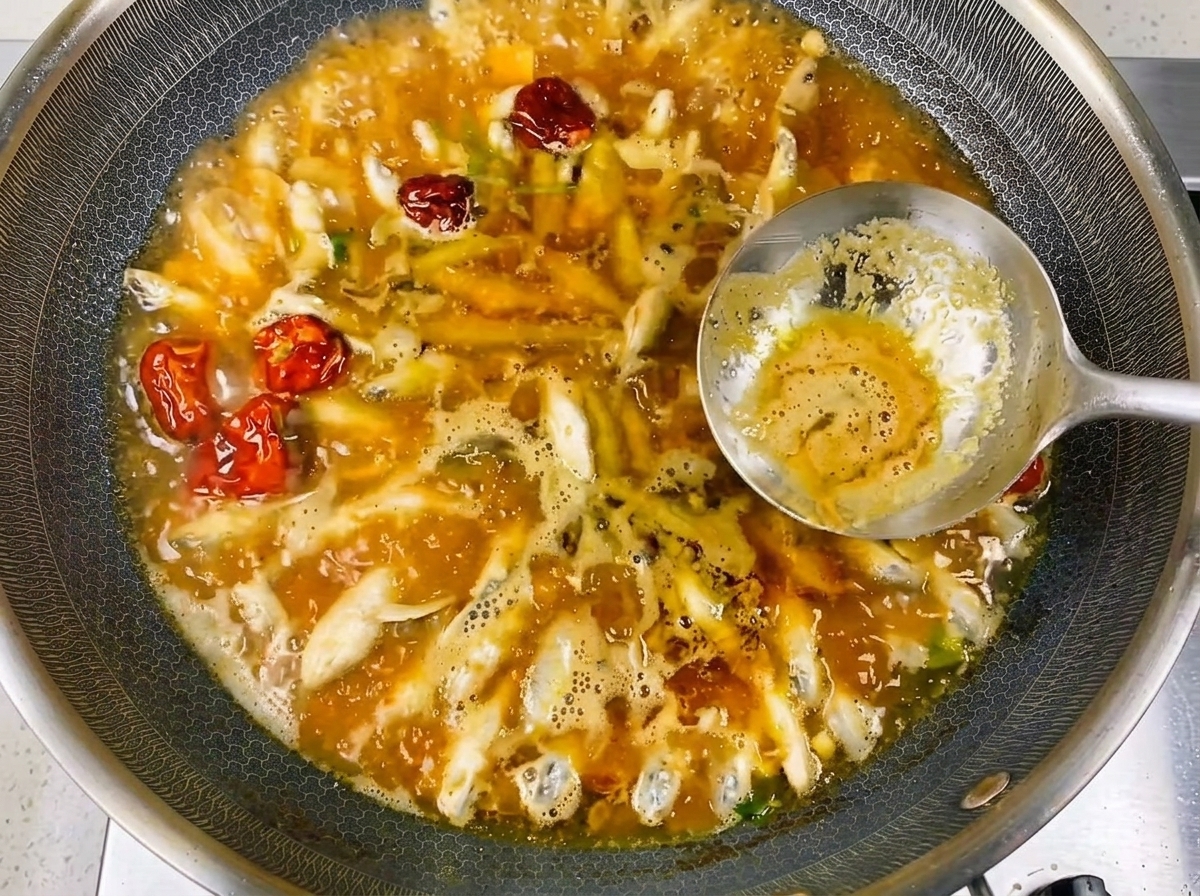 Gros plan sur les petits poissons de rivière bouillant dans un bouillon riche et savoureux avec des bulles visibles.