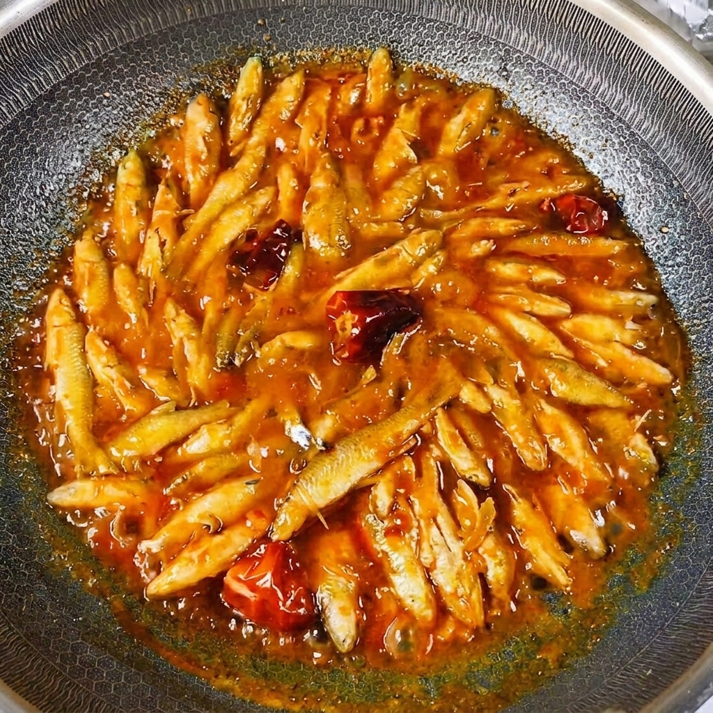 Les petits poissons de rivière cuits brillant avec une sauce savoureuse épaisse et réduite dans le wok.