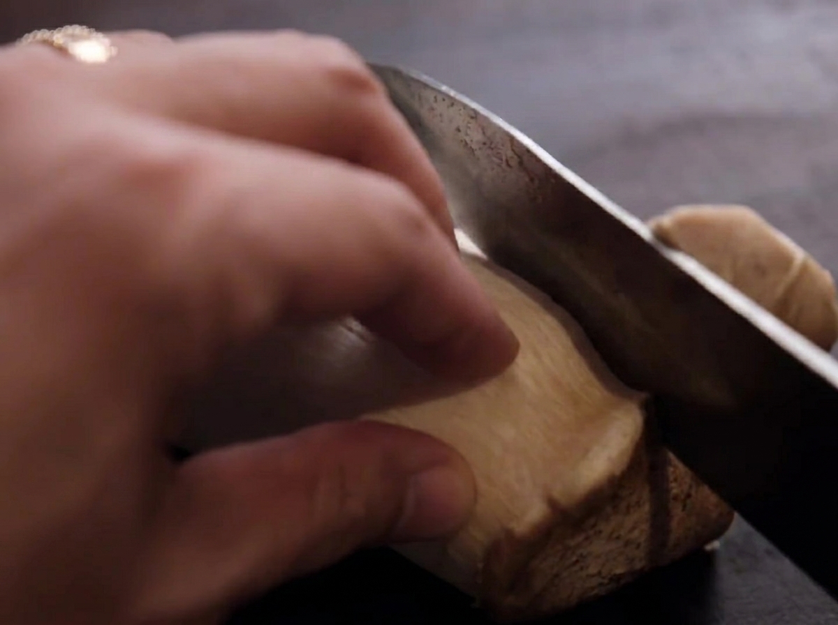 Champignons érigets tranchés sur une planche à découper en bois.