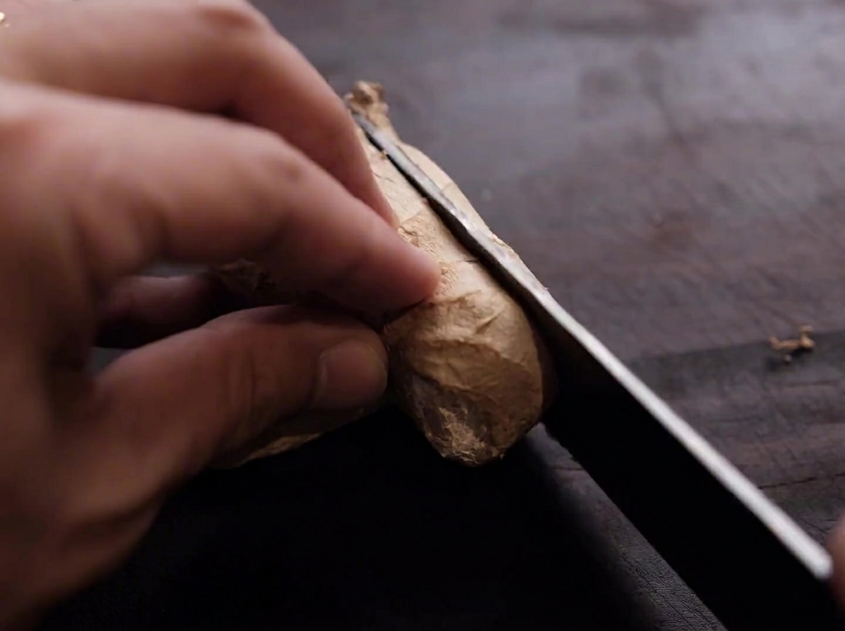 Gingembre frais coupé en fines lamelles sur une planche en bois.