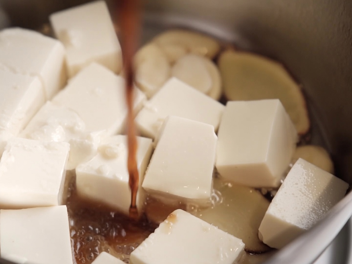 Sauce soja versée sur les cubes de tofu dans la casserole.