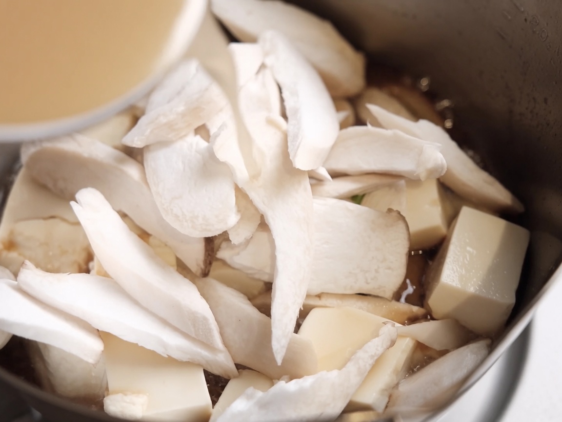 Mélange de miso versé dans la casserole sur le tofu et les champignons.