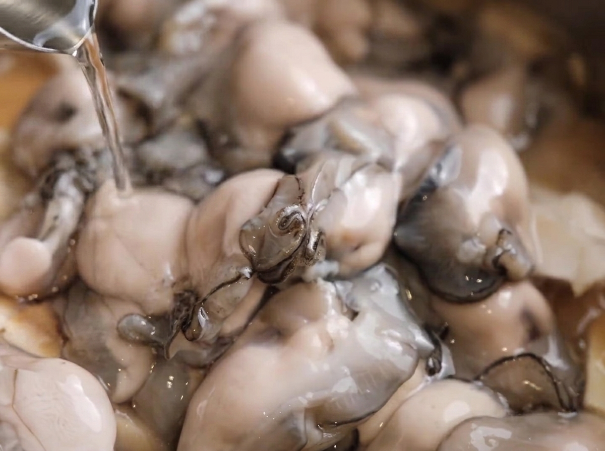 Poivre blanc saupoudré sur les huîtres dans la casserole.
